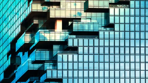 Modern glass building facade with layered balconies and reflections, symbolizing growth and transition.